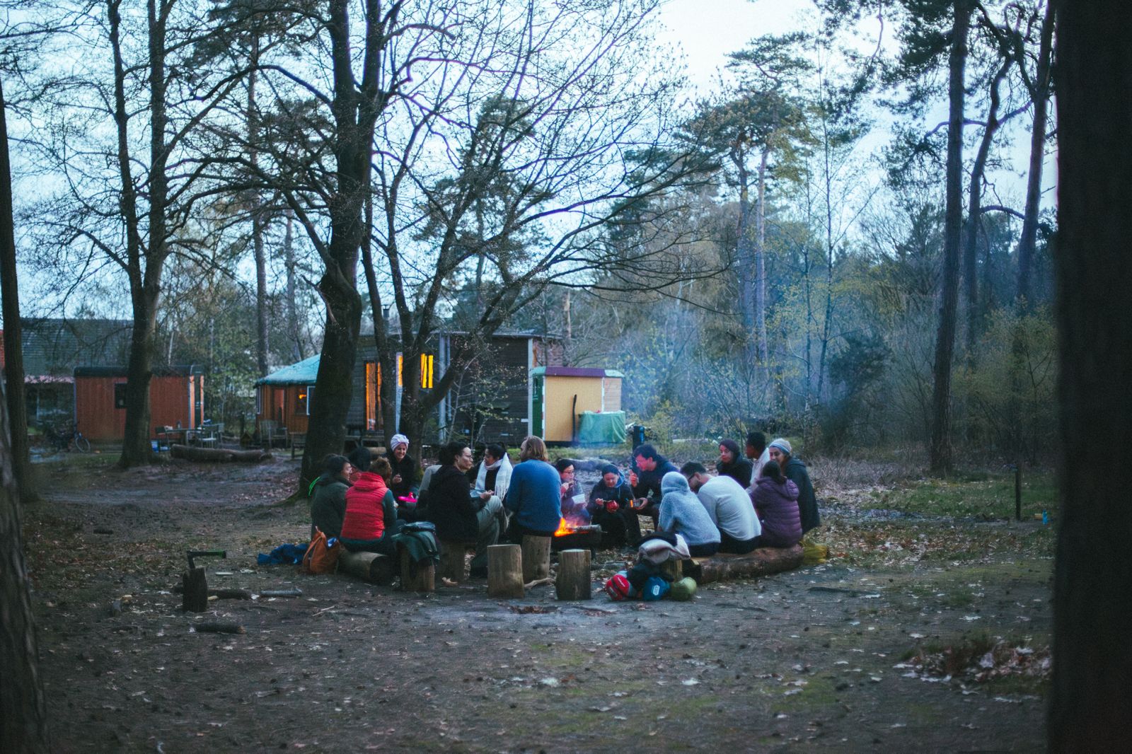 Group of 25 Rooted community members gathered around a fire